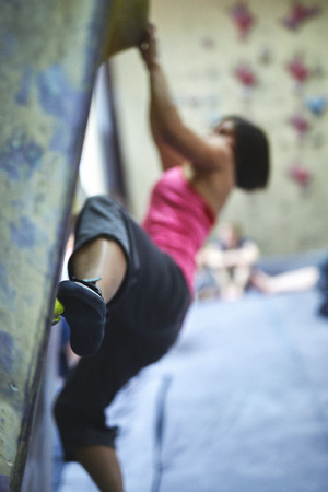 young woman climber climbs indoors in bouldering gym. focus on the feetの写真素材