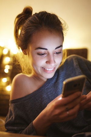 beauty woman using smartphone at home. woman lies on the sofaの写真素材