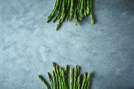 two bunches of fresh raw garden asparagus on gray concrete background. Ingredients for cooking. Food background. Top view with copy space.の写真素材