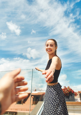 first person view of a Fashion pretty carefree woman posing on the amazing cloudy blue sky background in the center of old city of Lviv. woman admires the view of the cityscape from the rooftop with wonderful cloudy blue sky on backgroundの写真素材