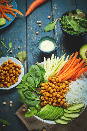 top view of ingredient set for cooking vegan food, fried chickpeas, rice noodles with wegetables on blue wooden table. Flat lay Vegan and raw eating buddha bowl, clean eating, healthy vegan food concept.の写真素材