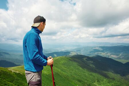 Active male hiker enjoying view of beautiful cloudy sky in mountains, travel and outdoor adventure concept. Carpathians, Ukraineの写真素材