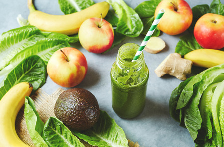 Ingredients for a tropical fruit green smoothie with avocado, peach and banana. A jar with green smoothies on a table among fruitsの写真素材