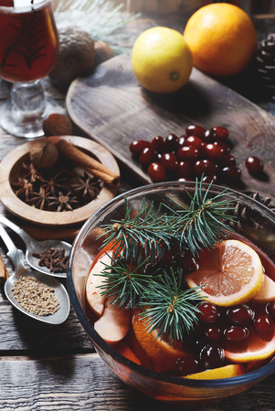 glass transparent bowl with Christmas hot mulled red wine with spices and fruits on a wooden rustic table with spruce branches. Traditional hot drink at Christmas timeの写真素材