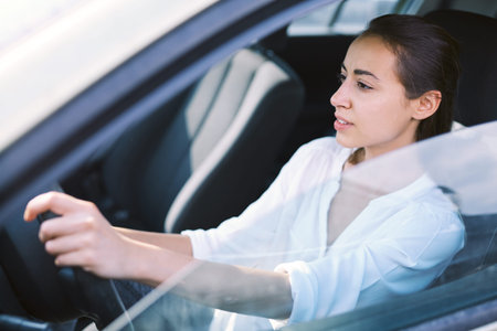attractive smiling woman driver in the car. woman is sitting in the car while driving, waiting at...