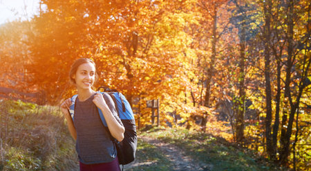 woman hiker with backpack walking outdoors. woman standing on the yellow tree background in mountain...