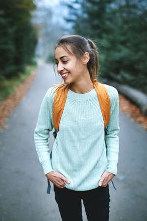 beautiful smiling woman hiker with small backpack standing on the road in the forestの写真素材