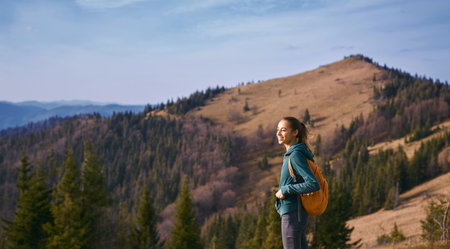 image of a happy woman hiker standing on the slope of mountain ridge on the mountains and blue sky...