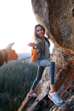first person view of a young pretty woman hiker climbed on the cliff, looking confused and getting helpの写真素材