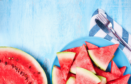 Watermelon slices on the blue plate on blue wooden table. Top view, flat lay. Summertime concept and vegan healthy food concept. Food backrgound.の写真素材