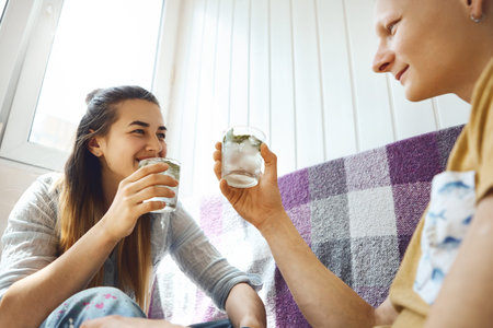 smiling Couple relaxing on sofa on balcony and holding glasses with cold mint lemonade. enamoured...