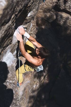 strong muscular man rockclimber climbing on tough sport route, reaching and gripping hold. outdoors rock climbing and active lifestyle conceptの写真素材