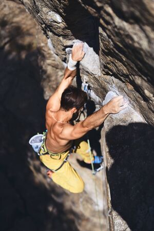 man rock climbing on tough sport route, rock climber makes a hard move. outdoors rock climbing and active lifestyle concept. Focus on the hands.の写真素材