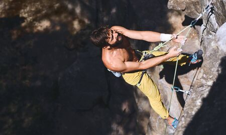 Close up portrait of strong muscular man rockclimber on tough sport route, resting and readying to climb. outdoors rock climbing and active lifestyle concept.の写真素材