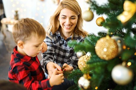 mom and son together decorating Christmas tree on the eve of holidays. Celebrating Christmas and New Year, having fun, happy time together.の写真素材