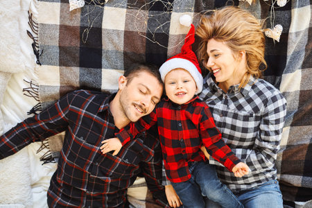 Christmas family spending time together at home, lying on the bed at home. Young parents and their...