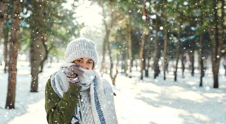 Winter outdoor portrait of of happy girl feeling cold and covering face with woolen scarf at snowly park at snowly park in frosty sunny day. Happy winter timeの写真素材