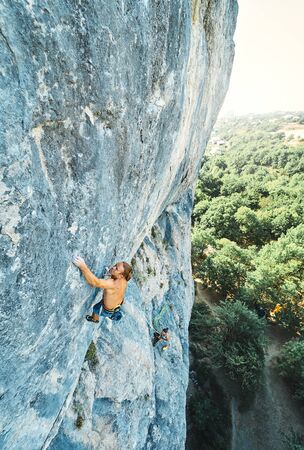 muscular man rockclimber with naked torso climbing on tough sport route. outdoors rock climbing and active lifestyle concept, climbing momentsの写真素材