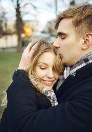 young man embracing and tenderly kissing his girlfriend, feeling comfortable, happy moments together. urban romantic portrait. Romantic, love and Valentine's Day concept.の写真素材