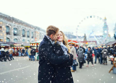 elegant romantic couple in love hugging and kissing on street with attraction at snowy day on background. Spending time together in the city, having a date. urban romantic portrait. Romantic, love and Valentine's Day concept.の写真素材