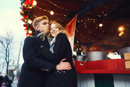 elegant romantic couple in love hugging and kissing on bright red festive decorations background. Spending time together in the city, having a date. urban romantic portrait. Romantic, love and Valentine's Day concept.の写真素材