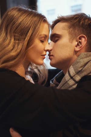 close-up portrait of young couple in love embracing with eyes closed, close to each other. happy moments together. having a date in cafe. Concept of first kiss, tenderness and loveの写真素材
