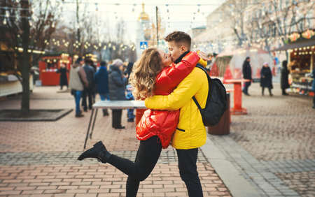 romantic couple in love kissing, hugging, walking on the street, wearning in bright down jackets. spending time together, having a date, urban background. Romantic, love and Valentine's Day concept.