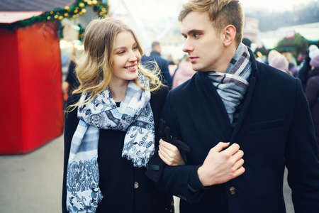young elegant couple walking city street in a crowd of people. boyfriend and girlfriend enjoying a date, wearing in black coats. urban romantic portrait. Romantic, love and Valentine's Day concept.の写真素材