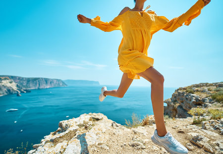 Close-up womans tanned legs making dinamic move, running on cliff against amazing seascape. Bright...
