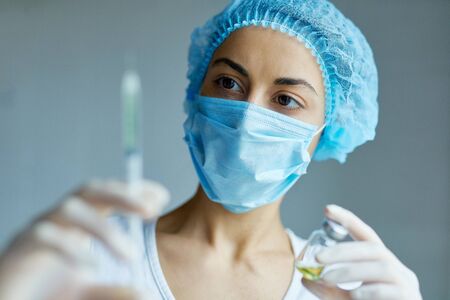 Woman doctor concentrate on syringe with liquid vaccines, preparing to injection. Dose flu shot drug, needle syringe, medical injection, diseases, health care. concept of vaccinationの写真素材