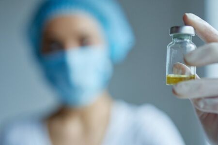Vaccine vial, bottle in hands in gloves. doctor or scientist in laboratory blurred on background. Prevention and treatment from coronavirus, flu, infection. Concept vaccination, medicineの写真素材