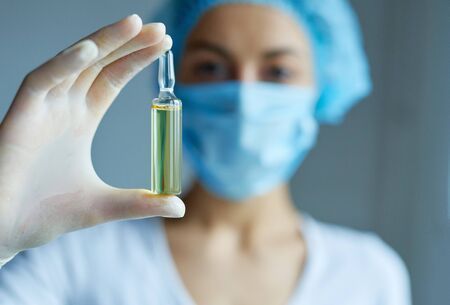 Doctor, nurse or scientist hand in gloves holding ampule with liquid drug. Vaccination from coronavirus, measles, dose flu shot drug. Prevention, immunization and treatment, health careの写真素材