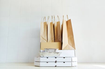Delivery during quarantine.Takeaway paper bags and carton boxes on table on white background. Takeout food, online order, deivery to homeの写真素材