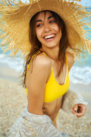 portrait of laughing smiling woman in big straw hat enjoying sea resort at seaside, summer holiday vacation, trendy beach styleの写真素材