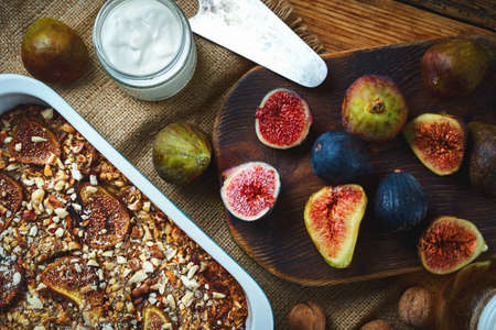 Top view baked delicious fruit pie with figs on breakfast with yogurt. Fresh whole and cuting figs on wooden cutting board on old wooden table backgroundの写真素材
