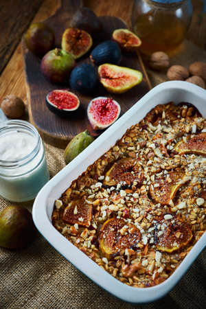 Homemade healthy autumn breakfast, baked oatmeel with figs and nuts, yogurt and fresh figs on wooden craft table on kitchenの写真素材