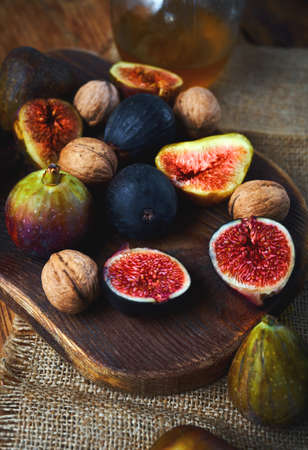 Autumn seasonal vitamin food. Fresh figs whole and sliced, walnuts, honey on craft kitchen backgroundの写真素材