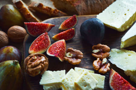 close up food image cheese with figs and walnuts on wooden cutting board on wooden table. Concept autumn food and snacks.の写真素材