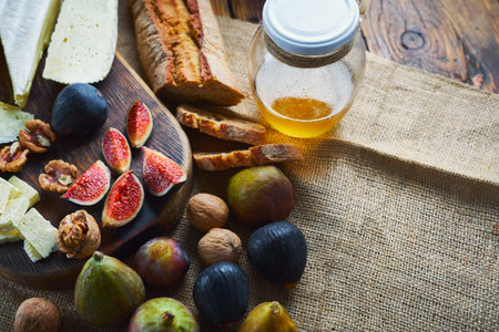 cheeseboard, fresh figs, whole wheat breadand and honey on sackcloth on table. Food for red wine....