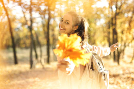 Autumn carefree woman with autumn leaves on fall nature background. Season and people conceptの写真素材
