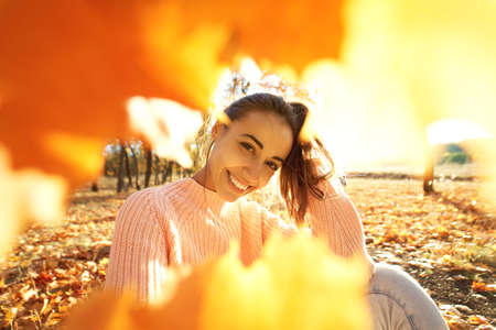 autumn portrait happy woman framed from fall leaves, colorful foliage and sunlights on background.の写真素材