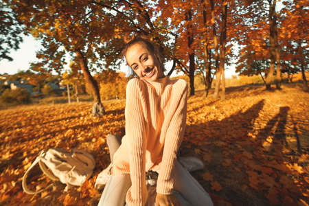 POV, first person view joyful woman in cozy sweater at sunlight autumn park witn colorful foliage, bright fallen leaves on backgroung. Autumn outdoors portrait.の写真素材