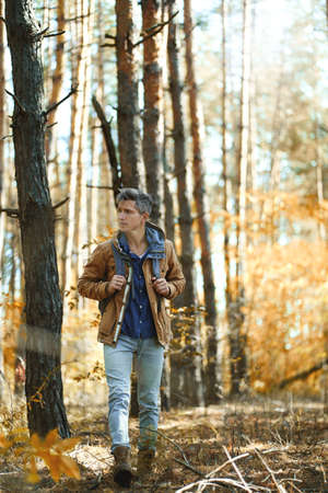 full leght portrait tourist hiker man in forest with backpack, walking in woods at autumn. Concept hiking, people in natureの写真素材