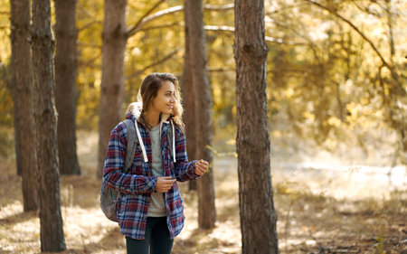 Woman traveler in sunny forest alone. Backpacker girl enjoying walking outdoors. Concept people and natureの写真素材