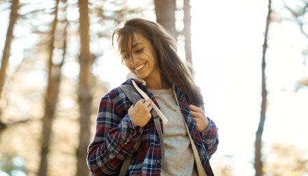 motion portrait optimistic smiling woman in forest with sun lights on background. Concept wellness, active vacations outdoor. focus on shoulderの写真素材