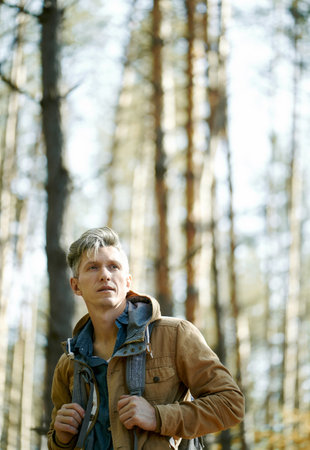 portrait backpacker man standing in forest, optimistic looking forward, sunny weather. slow living conceptの写真素材
