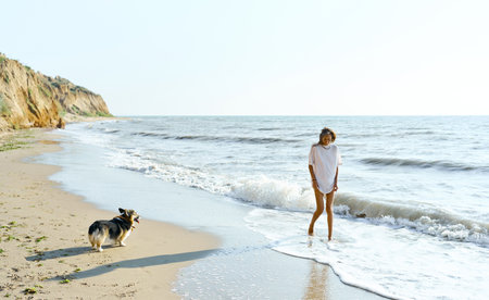 Suntanned positive girl with her pet walking along shore of summer beach at morning together. slow living conceptの写真素材