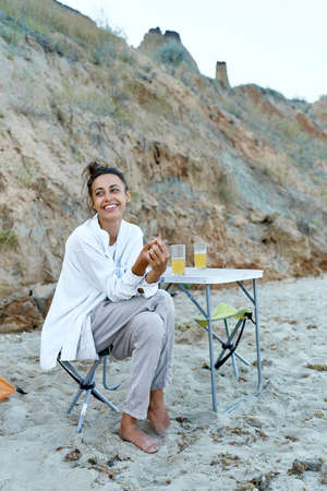 Cheerfulness camp woman sitting on camping chair, feeling good at beach. Concept authentic people, candid portraitsの写真素材
