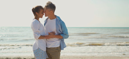 romantic couple embracing, holding hands and smiling to each other. two lovers have a date at sunny beach. love, honeymoon, valentines dayの写真素材