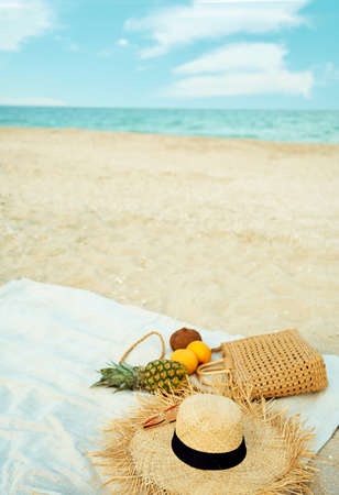 Set of summer fashion beach accessories and fresh fruit on sandy beach against blue sea and sky background. Summer vacation conceptの写真素材